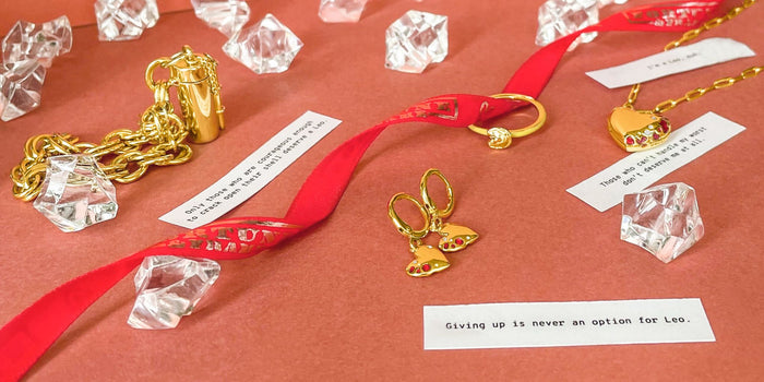 Jewelry pieces with plastic crystals, fortunes and a red ribbon over an orange background.